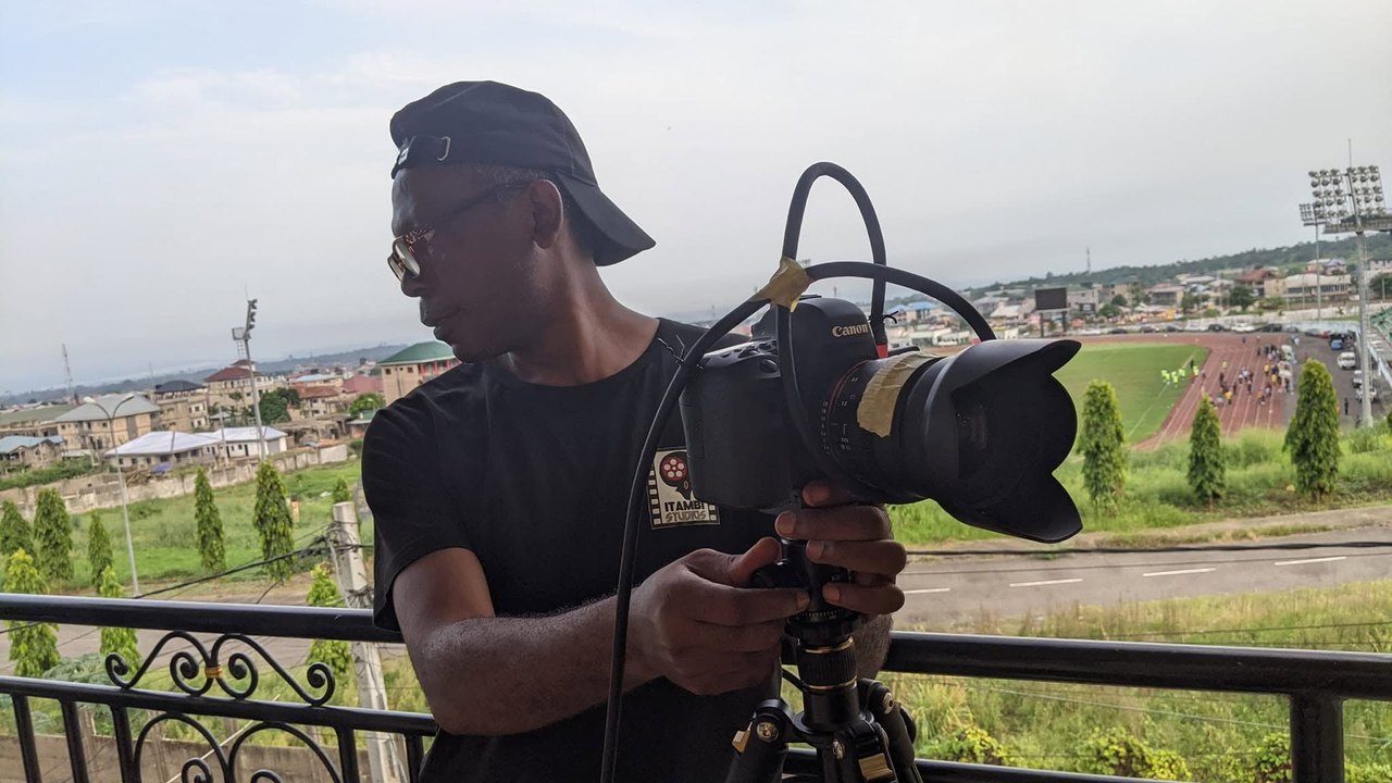 A camera operator carries a cinema camera on location.