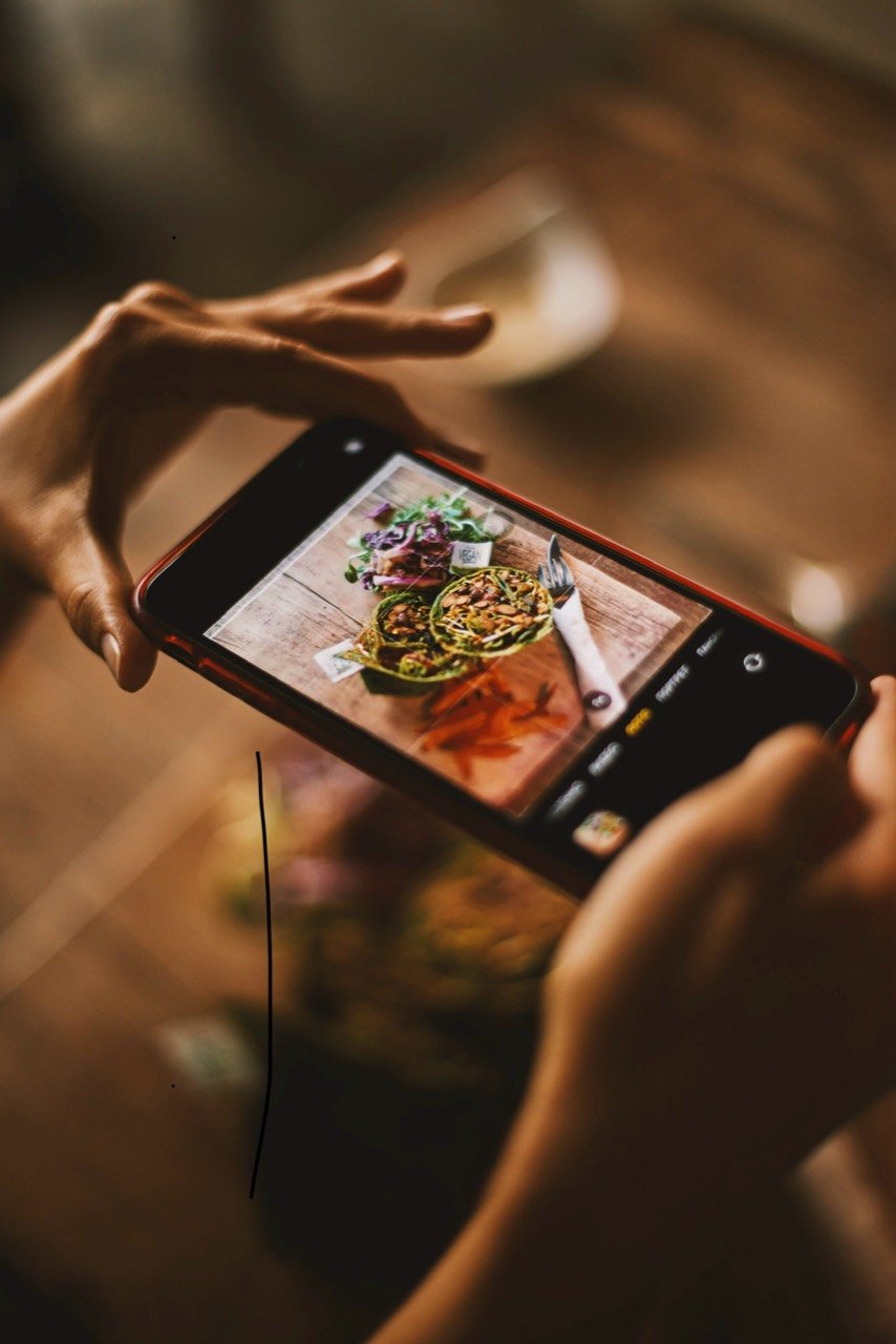 A content creator photographing food with a smartphone.