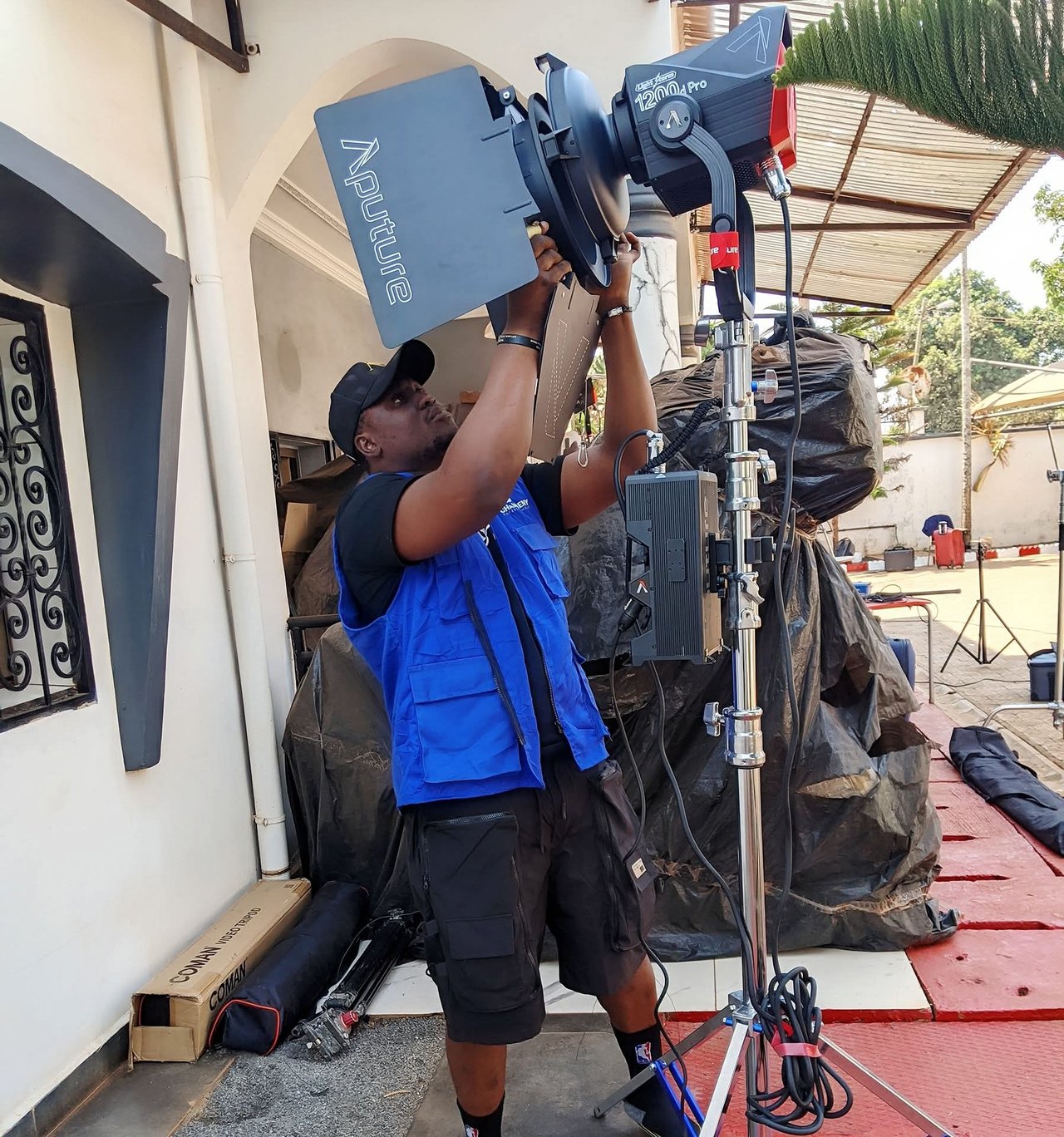 A crew member adjusts a film light on a production set.
