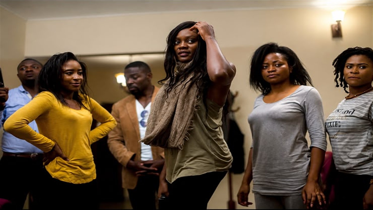 Cast members standing together in a hallway during a dramatic scene.