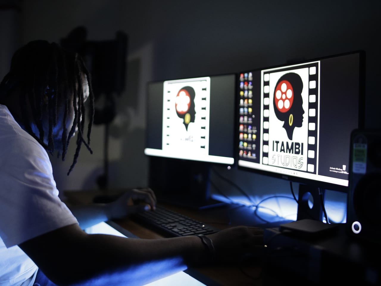 Editing workstation with dual monitors displaying Itambi Studios branding.