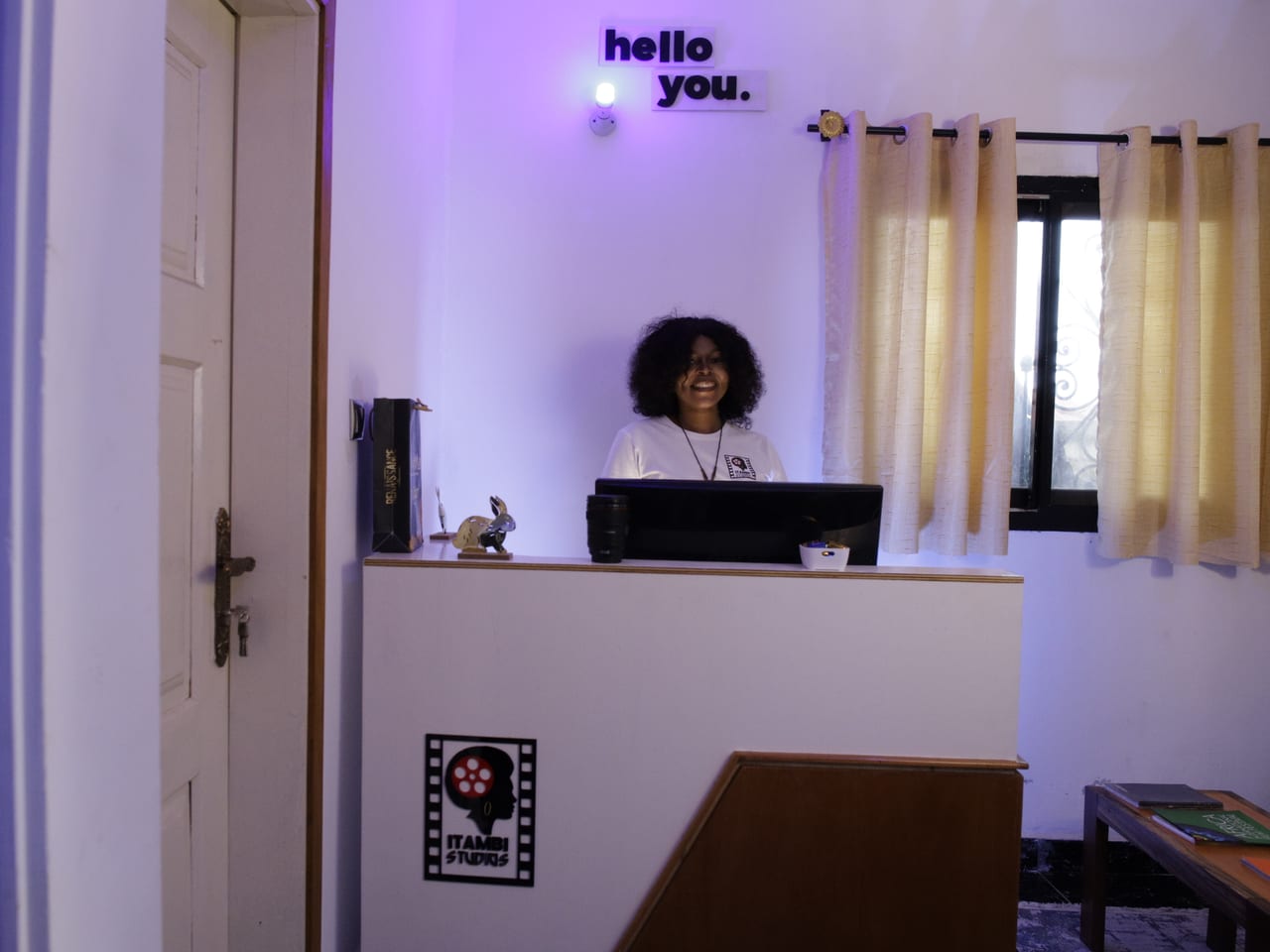 Itambi Studios reception desk beneath a lit wall sign, with a branded film-reel decal.
