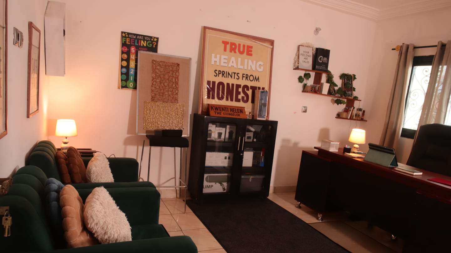 Studio lounge with sofa seating, framed prints, shelving, and a wall poster.