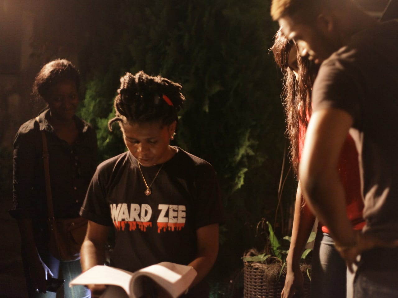 Crew members reviewing a script together on set at night.